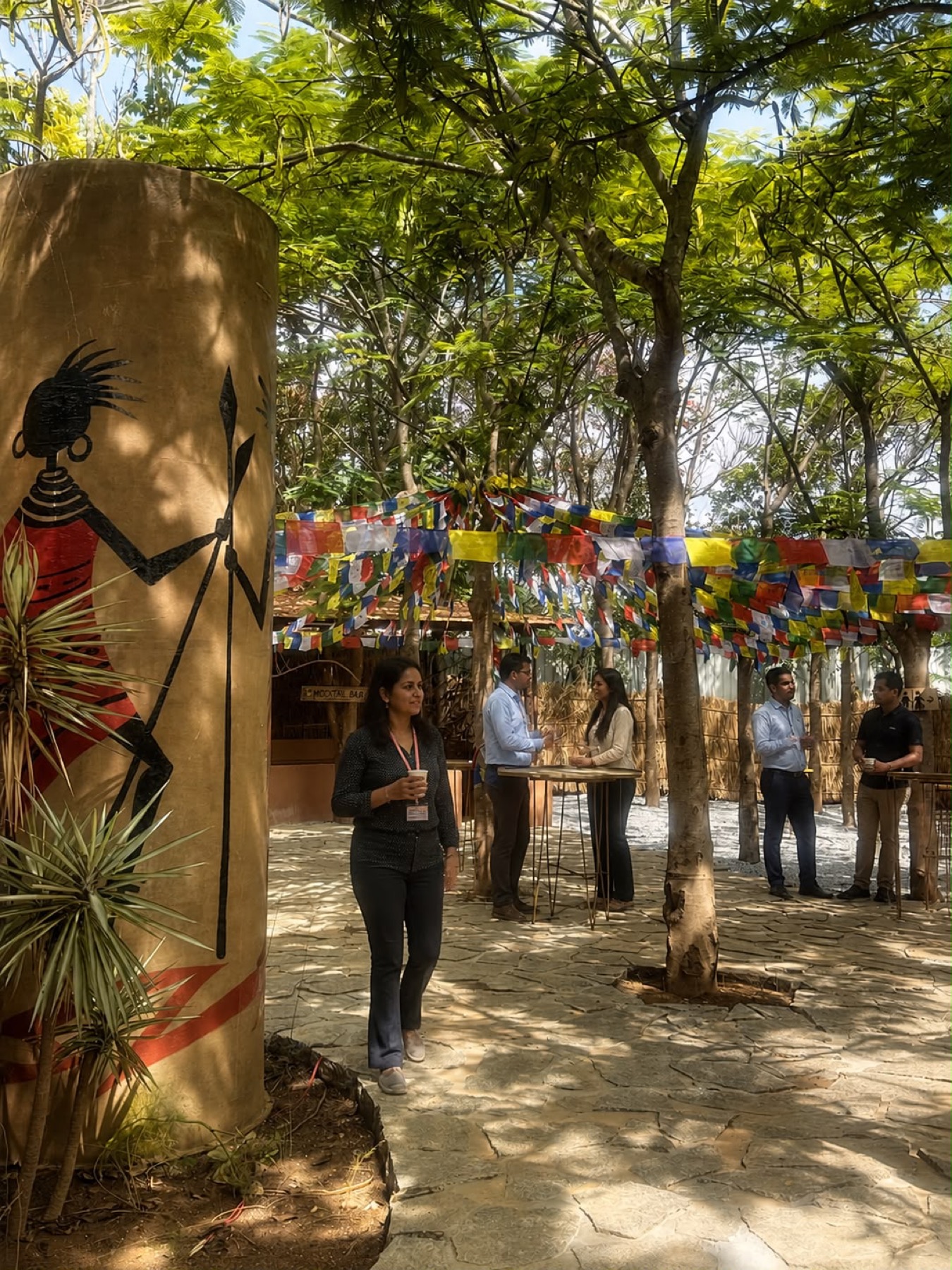 Colleagues at an outdoor breakout under prayer flags and trees at Orchid Tree